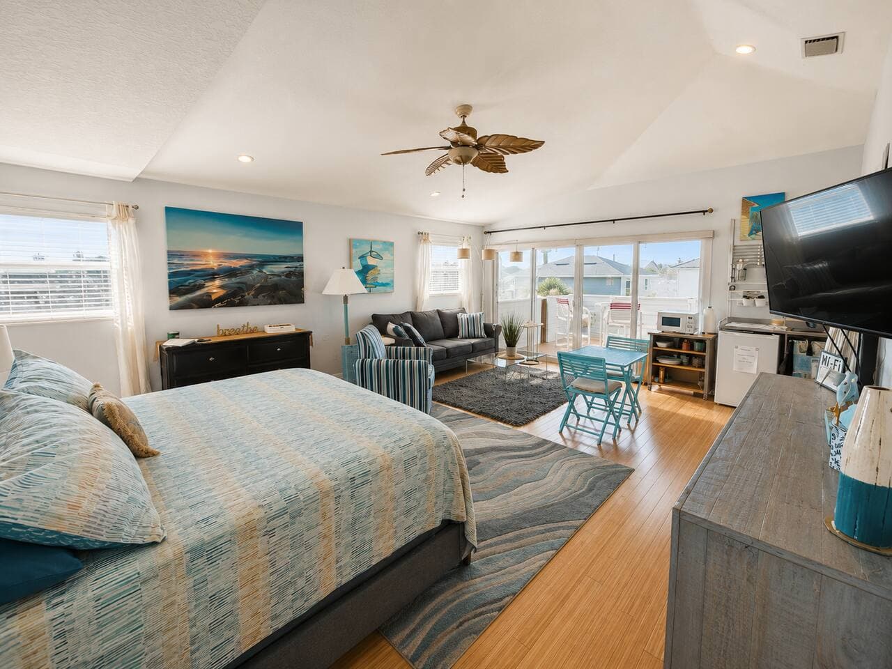 Bright coastal studio with king bed, sitting area, and sunny patio access