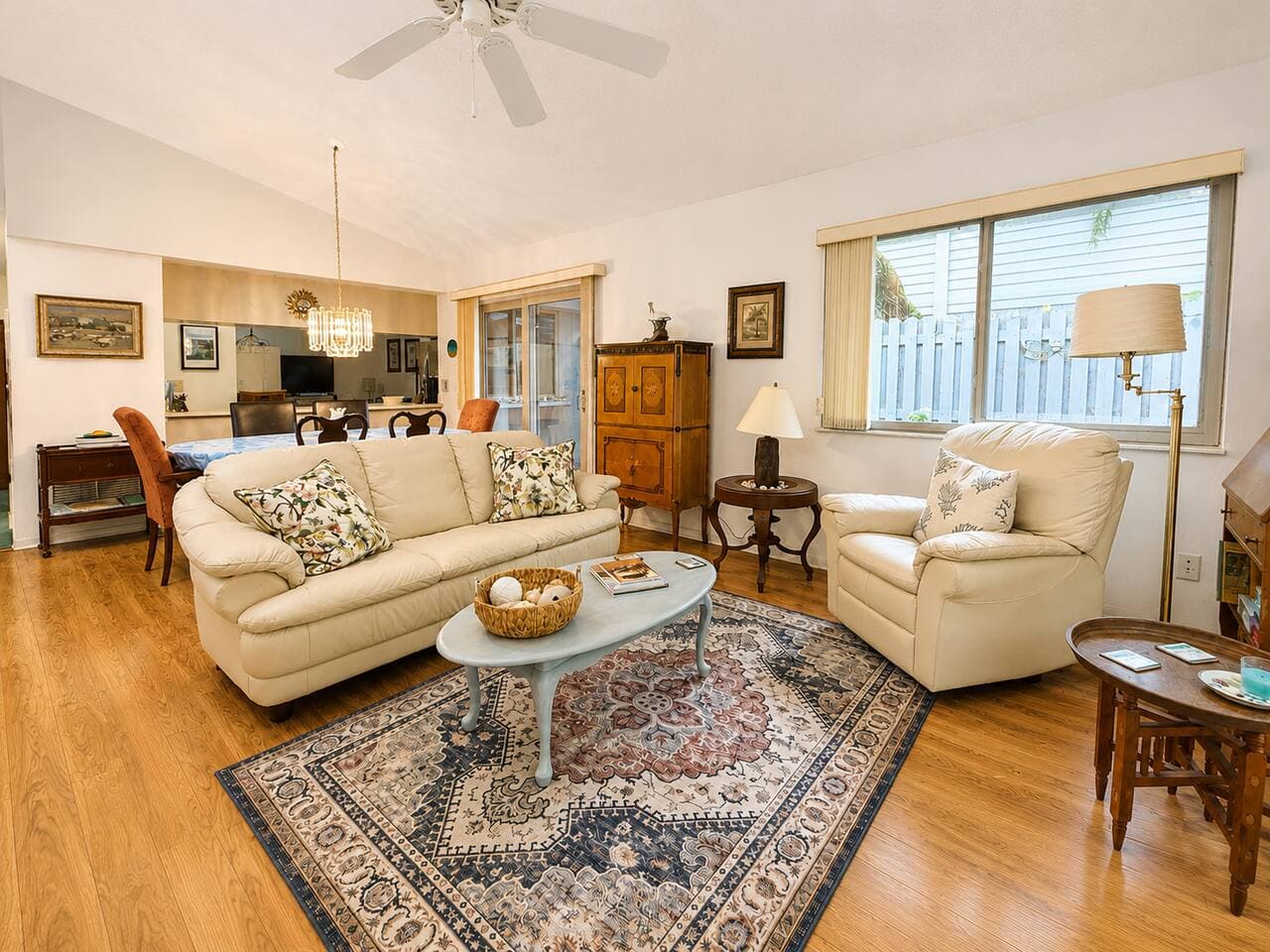 Living room with vaulted ceiling, cream leather sofa and recliner, area rug, opening to the dining area